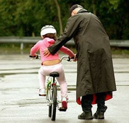 Training - A man training a child how to ride bicycle